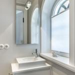 Badezimmer mit Waschbecken, Spiegel und Fenster mit Jalousie.