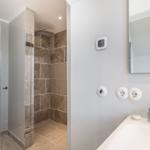 Dusche mit Steinwand, Waschbecken und Spiegel