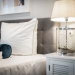 Schlafzimmer mit Bett, Kissen und Nachttisch mit Lampe.