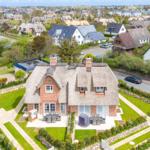 Haus mit Strohdach, Garten und Terrasse. Blick auf Wohnsiedlung.