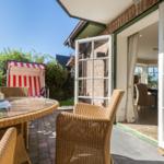 Terrasse mit Esstisch, Stühlen und Strandkorb. Durchgang ins Haus.