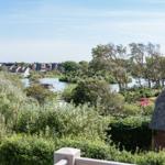 Peaceful view of river and houses with green vegetation and thatched-roof house.