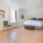 Bedroom with bed, window, wall art, and wooden floor.