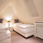 Two beds and a crib in an attic room with skylight.
