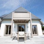 Modern villa with terrace and garden area under blue sky.
