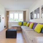 Living room with L-shaped sofa, colorful cushions, and TV mounted on wall.