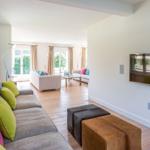 Living room with sofa, TV, and hardwood floor. Passage to balcony with seating area.