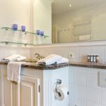 Badezimmer mit Waschbecken, Spiegel und Handtuchhalter.