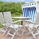Terrasse mit Tisch, vier Stühlen und Strandkorb mit blau-weißem Streifenmuster.