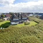 Dorfhaus mit Strohdach und Garten in grüner Landschaft