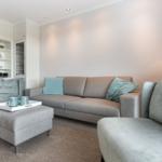 Living room with sofa, armchairs, and ottoman. Background: white cabinets.