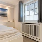 Bedroom with white bed, window, and radiator.