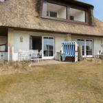 House with thatched roof, terrace, and beach chairs in the garden.