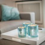 Three blue candle holders on a white tray in front of a sofa.