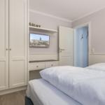Bedroom with double bed, wardrobe, and TV mounted on the wall.