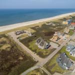Aerial view of coastal village with thatched houses and sandy beach.