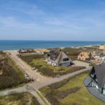 Houses with thatched roofs and modern buildings near the coast.