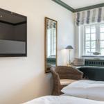 Zimmer mit Bett, Fernseher, Spiegel und Fenster mit Jalousie.