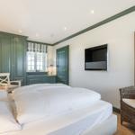 Schlafzimmer mit Bett, Kleiderschrank und Fernseher an der Wand.