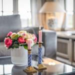 Auf Tisch: Blumenstrauß, brennende Kerzen in blau-goldenen Haltern.