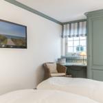 Schlafzimmer mit Bett, TV und Kleiderschrank. Fenster mit Streifenrollo.