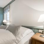 Schlafzimmer mit Bett, Nachttisch, Lampe und Kleiderschrank.