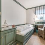 Ein Schlafzimmer mit Bett, Stuhl und Fenster mit Vorhang.