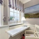 Schreibtisch mit Stuhl unter Fenster, Wandbild und Lampe