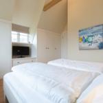 Schlafzimmer mit Doppelbett, Kleiderschränken und Wandbild.