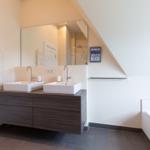 Badezimmer mit Doppelwaschbecken, Badewanne und Spiegel