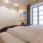 Schlafzimmer mit Bett, Kleiderschrank und Fenster.
