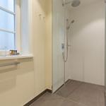 Dusche mit Glaswand, Fenster und Badewannenrand