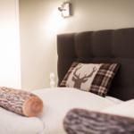Doppelbett mit Kissen und Holzrollen auf weißer Bettwäsche