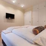 Schlafzimmer mit Bett, Kleiderschrank und Wandfernseher.