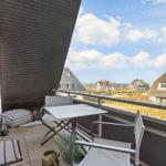 Terrasse mit Tisch und Stühlen, Blick auf Dächer und Meer