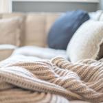 Ein Sofa mit Kissen und einer gestrickten Decke.