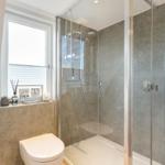 Bad mit Dusche, Toilette und Fenster mit Dekoration.