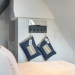 Schlafzimmer mit Dachschrägen, Bett, Wandhalter und Kissen.