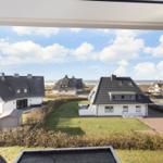 Weitläufiger Blick auf mehrere Häuser mit Dächern und Grünflächen am Strand.