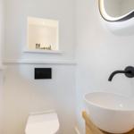 Bathroom with sink, mirror, and toilet. Black fixtures and wooden vanity.