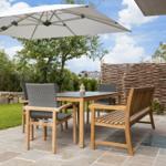 Terrace with table, chairs, and umbrella. Background: greenery and wicker fence.