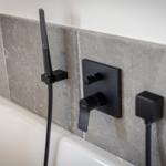 Showerhead and faucets mounted on wall above bathtub