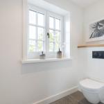 Bathroom with toilet, window, and wall art.