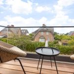Terrace with chair and table, view of traditional houses with thatched roofs.