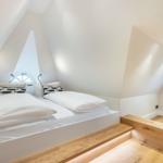 Bedroom with double bed, wooden steps, and round window.