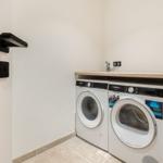 Washing machine and dryer in a room with wooden countertop and white door.