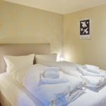 Bedroom with bed, towels, and wallpaper with lobster motifs.