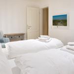 Bedroom with white bed, blue seating, and wall picture.