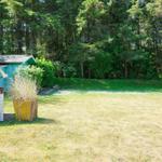 Green garden with beach chair and small house in the background.