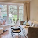 Living room with sofa, armchairs and table. French doors lead to the terrace.
